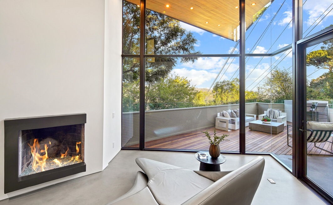 Fabulous fireplace in a living room with incredible wall of glass for even more views.