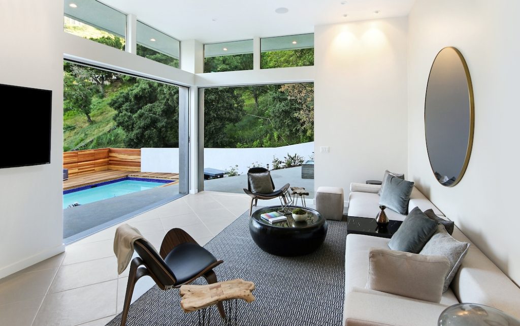Open living area includes walls of glass that open to the sparkling pool and yard.