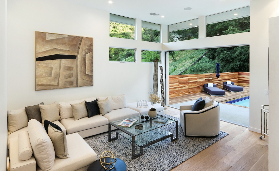 Open living area includes walls of glass that open to the sparkling pool and yard. 