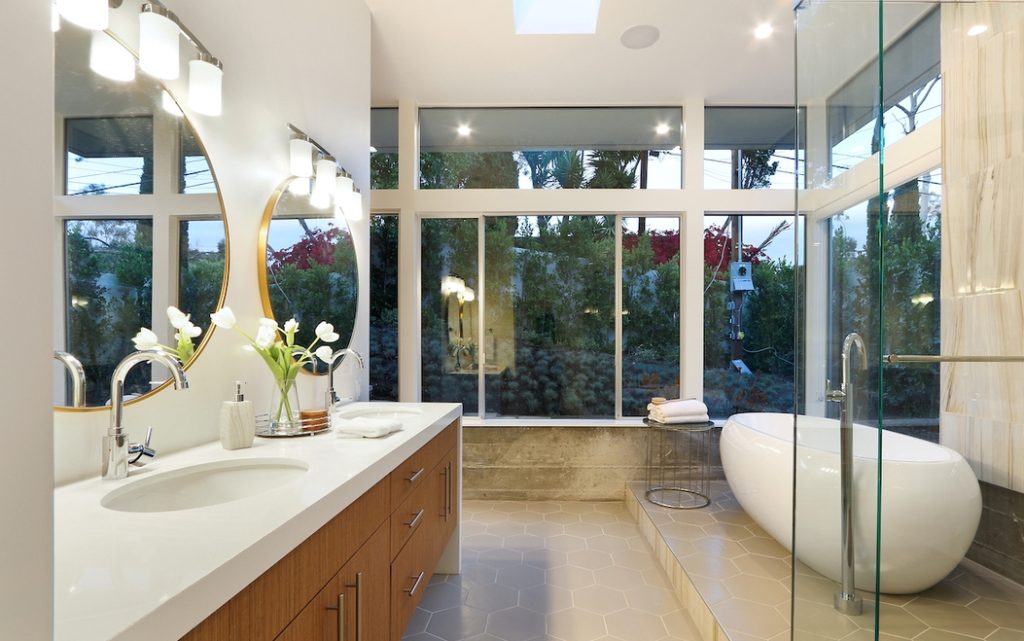 Incredible freestanding tub sits next to a wall of glass for views to the garde.