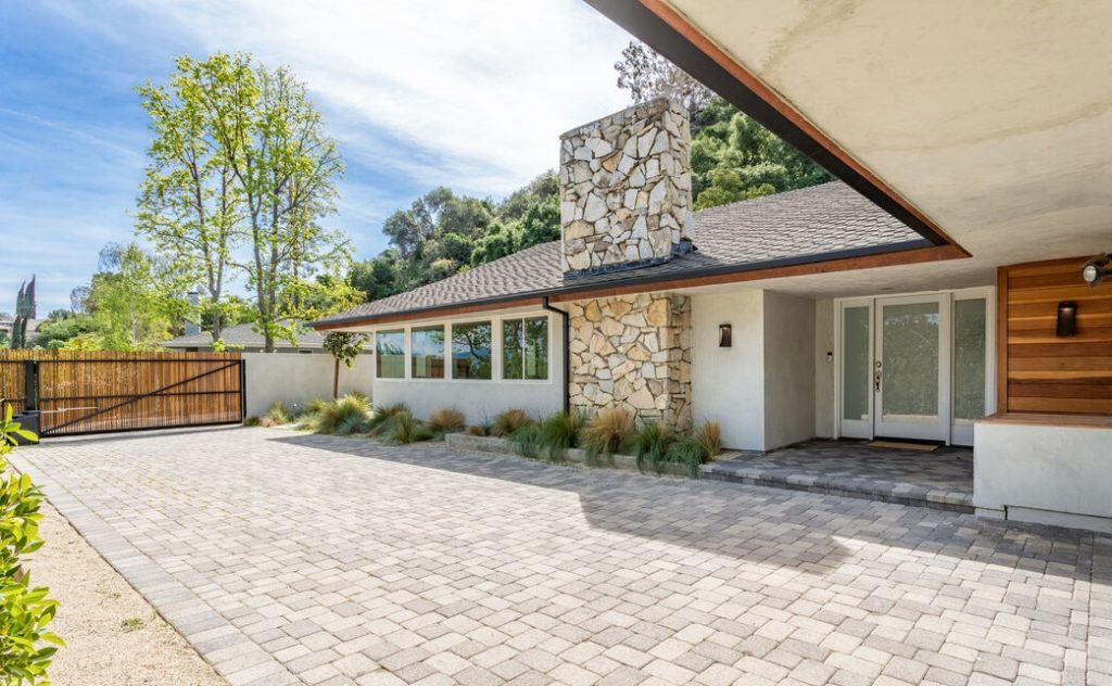 Huge driveway alongside this mid century home, behind privacy gates.