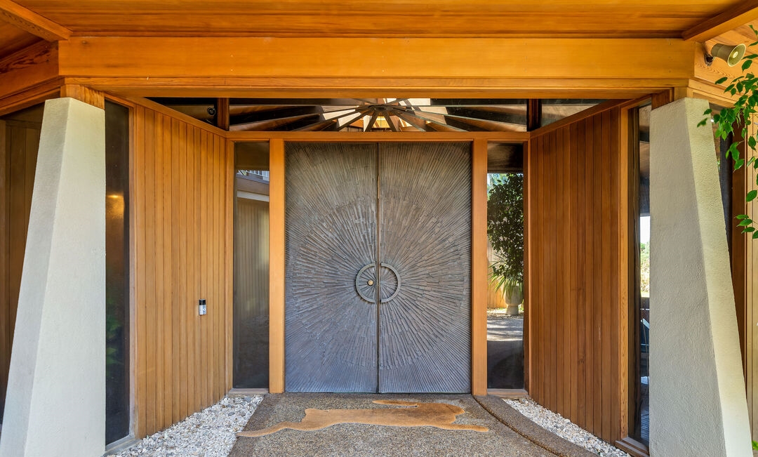 Incredible woodworking presents a grand original bronze clad Sunburst front door.