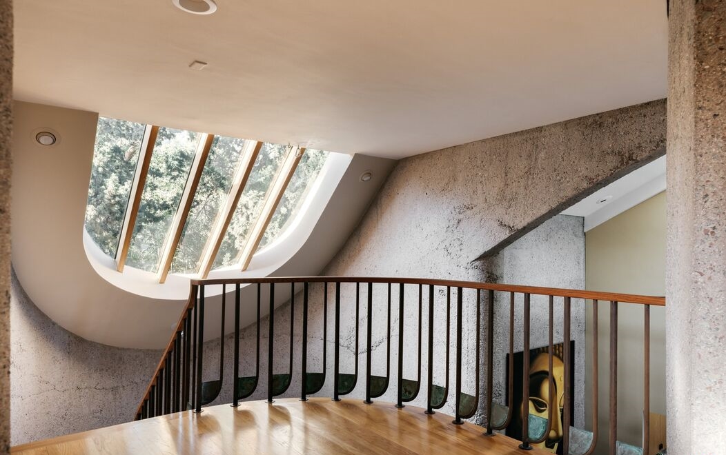 A breathtaking sweeping entry comprised of curved aggregate concrete with dramatic windows and staircase.
