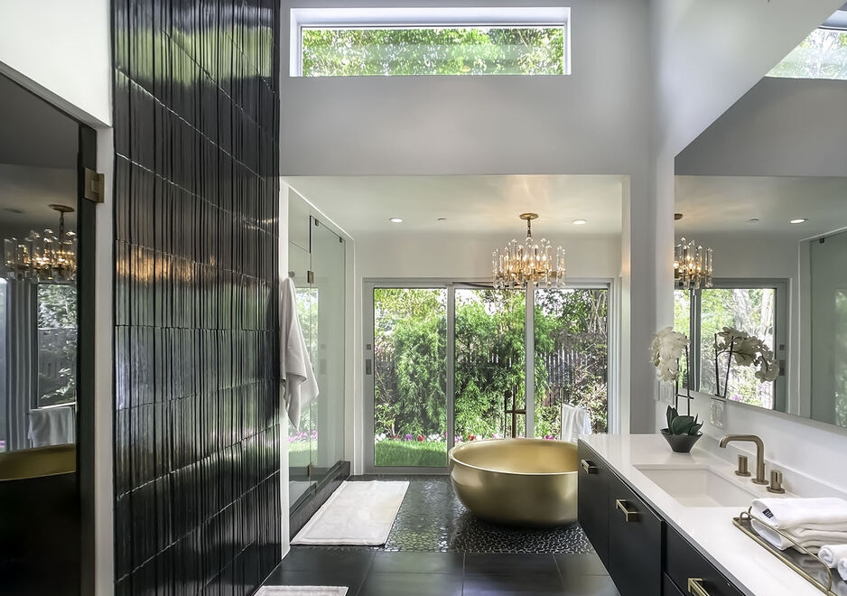 Unbelievable grand freestanding round soaking tub in a bathroom with dramatic wall of black tile.