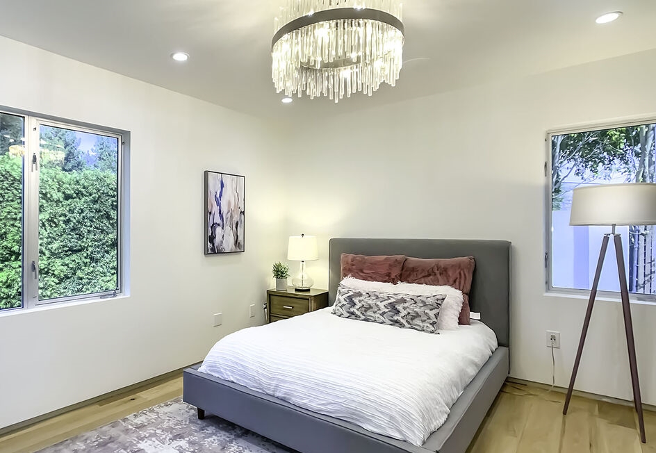 Lovely secondary bedroom with fabulous chandelier. Abundance of light through walls of windows.  