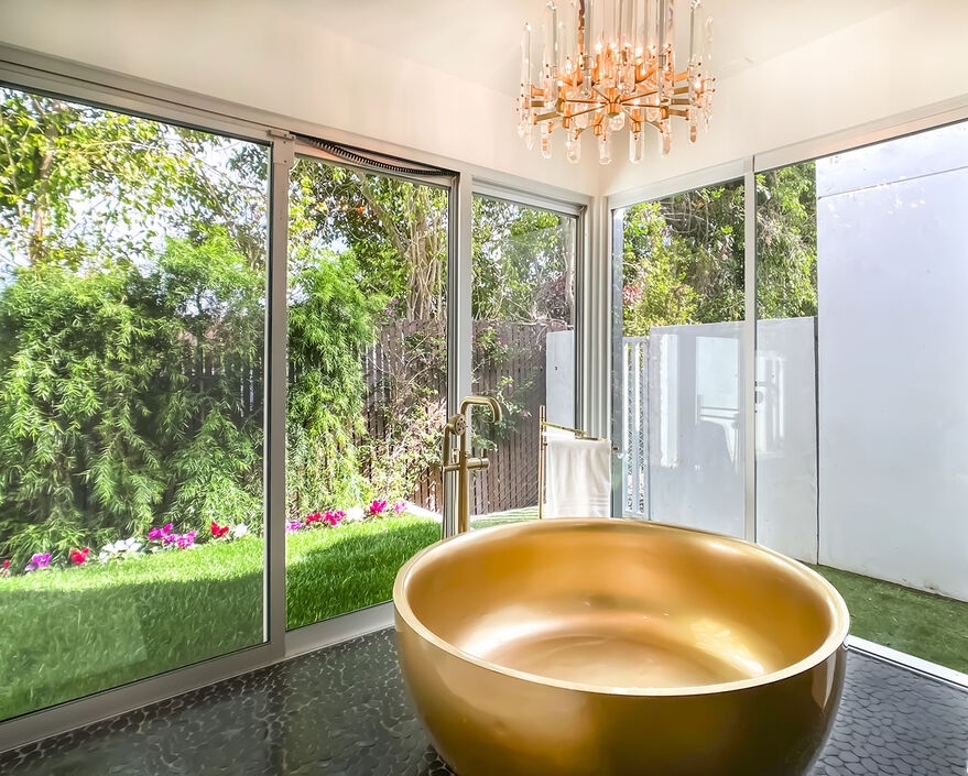 Unbelievable grand freestanding round soaking tub in a bathroom with dramatic walls of glass opening to the lush grounds.