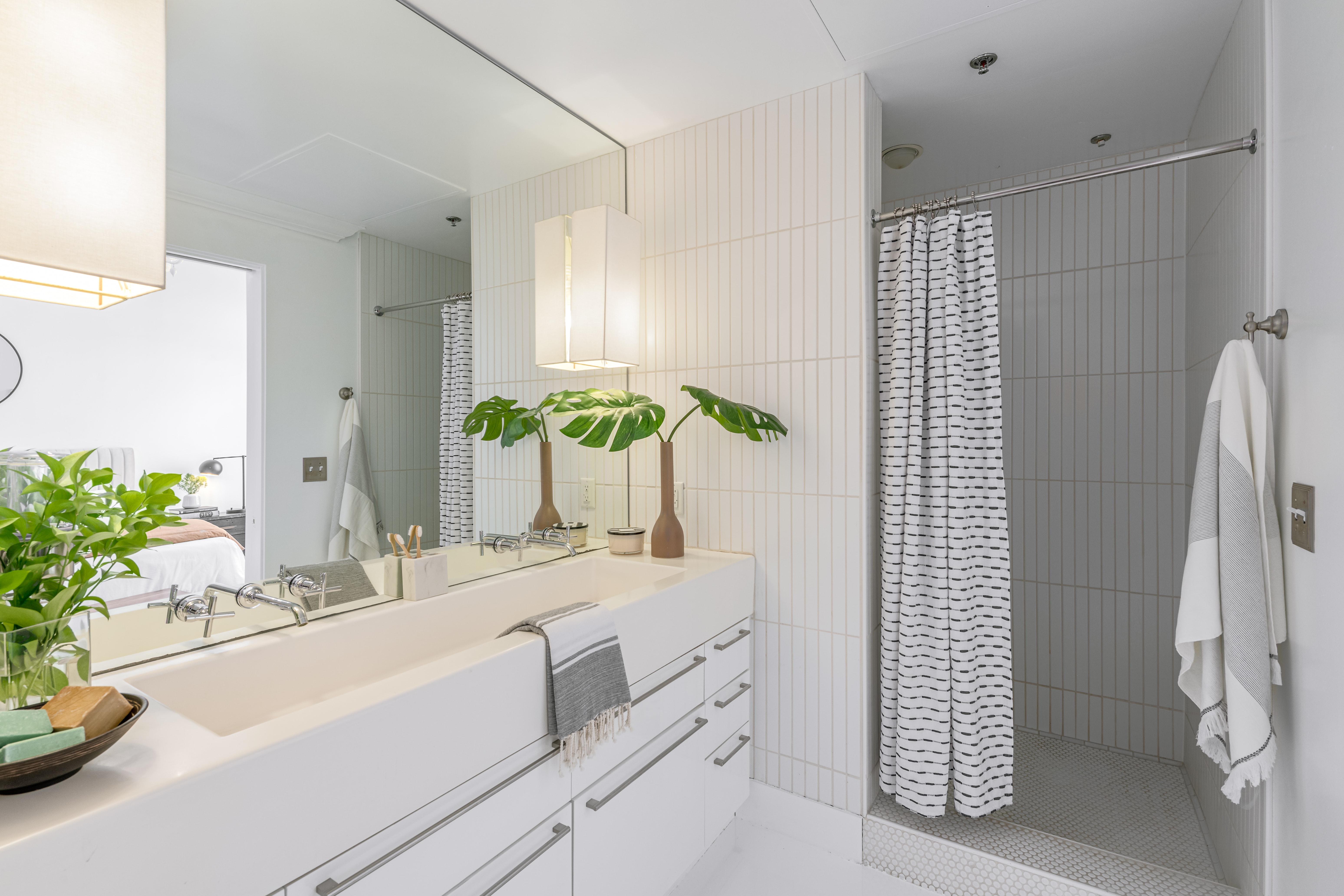 Sleek lines, oversized vanity, and white tiles in this primary bath.