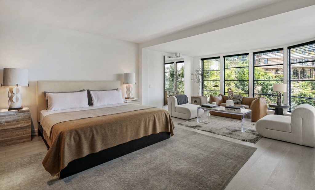 Oversized primary bedroom with sitting area and walls of windows.