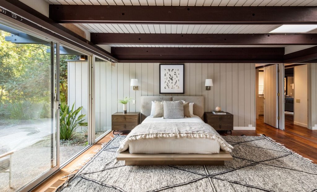 Walls of glass and stunning post and beam ceilings in Two separate bedroom wings allow simple functionality; three bedrooms on one side of the house and the primary suite on the other.