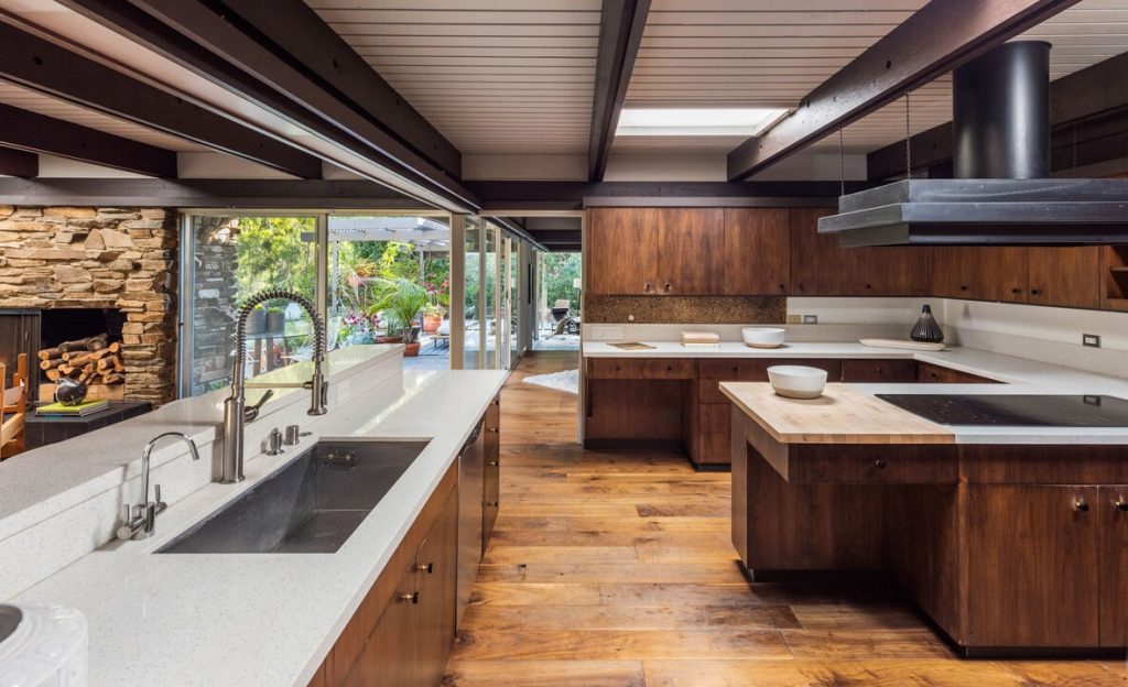 The open plan kitchen seamlessly shares space with the family room with half walls and brick fireplace.