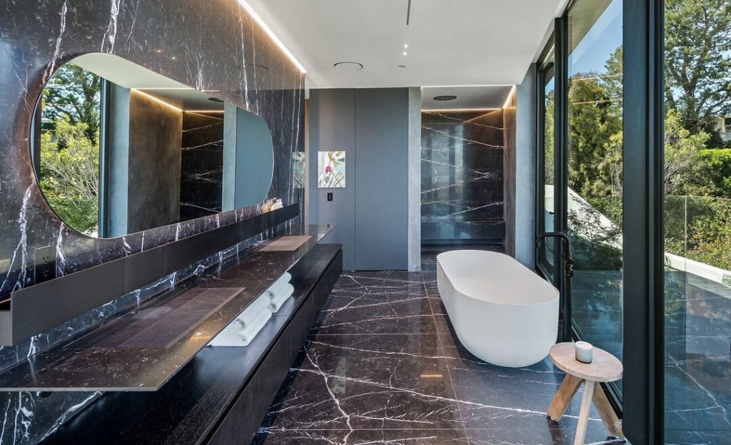 The en suite primary bathroom is adorned with Nero Marquina marble slab walls and flooring with matching Agape sinks and faucets.