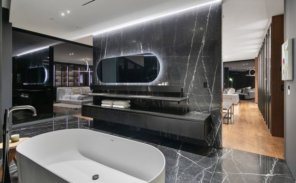 The en suite primary bathroom is adorned with Nero Marquina marble slab walls and flooring with matching Agape sinks and faucets.