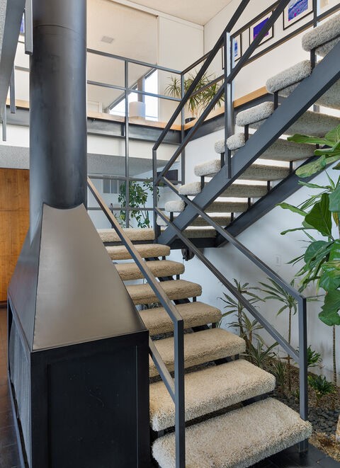 Using an inverted plan, the street-level entrance leads directly to the second floor, with public spaces oriented around a central two-story core, anchored by a wood-burning fireplace at the heart of the home. 
