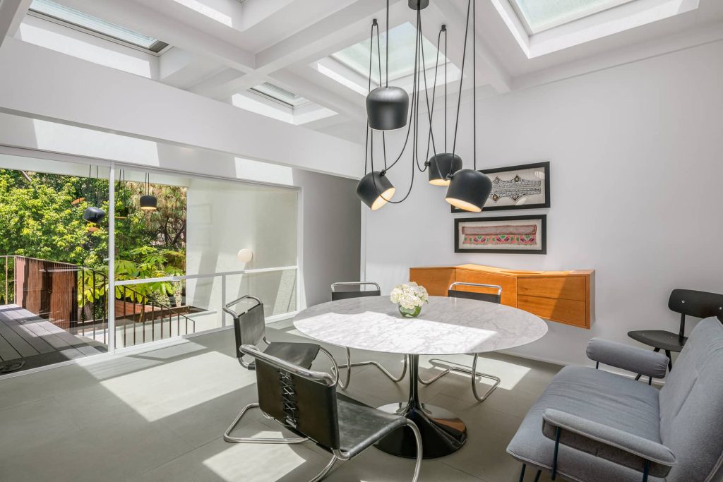 Clean lines, white walls, skylightsw, and walls of glass out to the grounds in this remarkable dining area