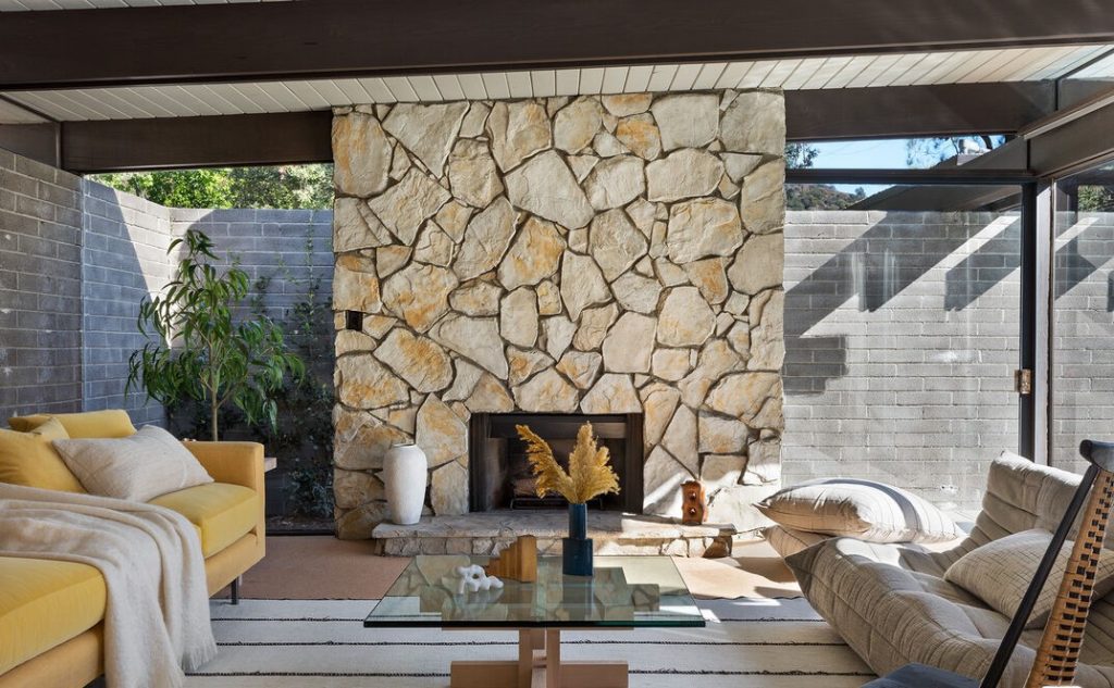 Massive stone fireplace, Horizontal massings of redwood siding and unpainted masonry block give privacy to a glass walled pavilion.