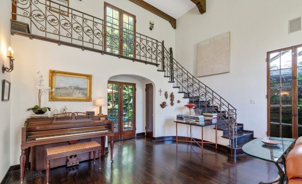 dramatic 2-Story living room with a stunning interior staircase, imposing fireplace and mantel, and a spectacular floor to ceiling leaded glass window overlooking your private front yard