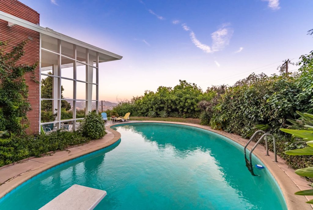A classic sparkling kidney shaped swimming pool tops off the modern vibe.