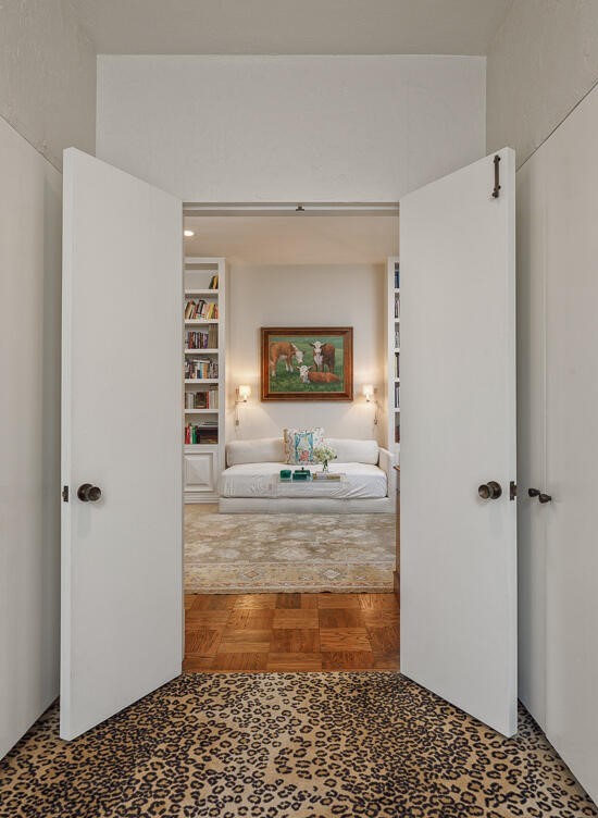 The primary bedroom faces out to the pool with glass doors and features a fireplace with a striking marble surround.