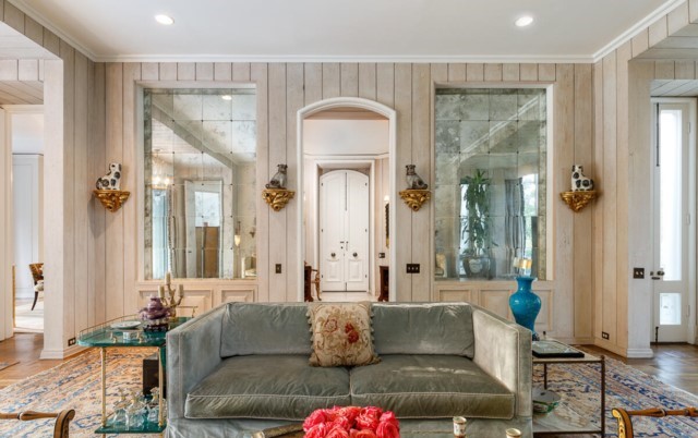 Through the 10 foot double door entry, the foyer is clad in a beautiful tongue and groove planking which extends to the living room, where a curved wall of floor to ceiling glass surrounds an ornate marble fireplace.