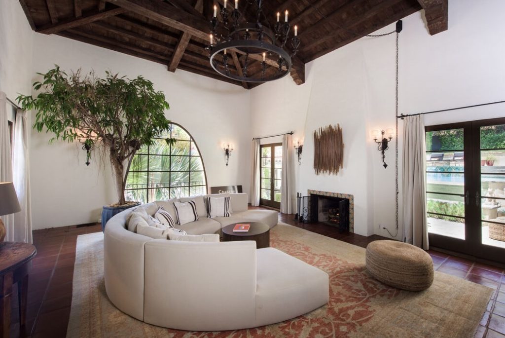 A stone driveway and steps lead to a discreet entry into a dazzling double-height living room with stenciled and beamed ceiling