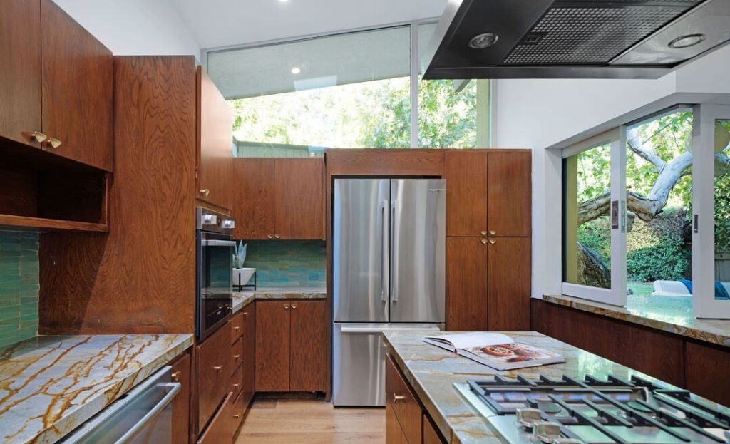 the kitchen featuring marble countertops, imported tile, and top of the line appliances with indoor/outdoor 3D pocket serving window.