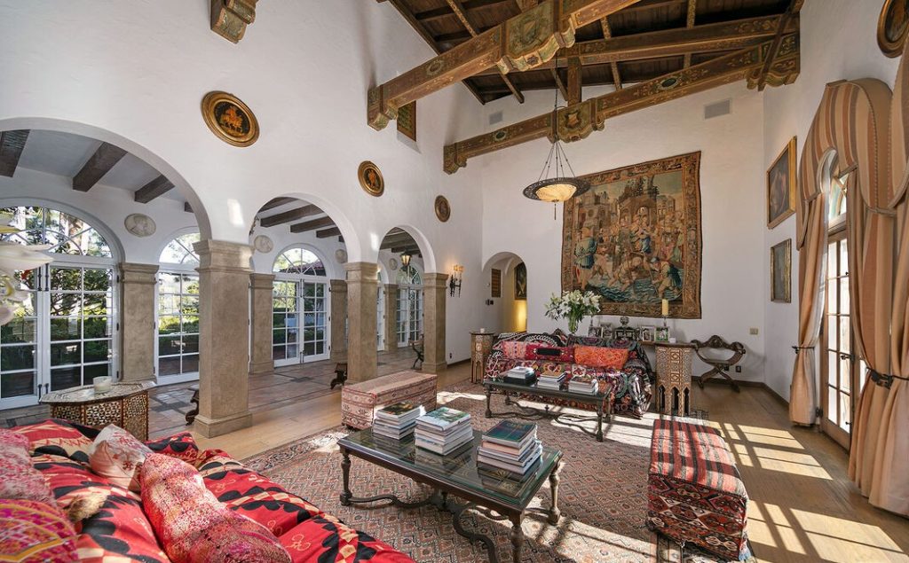 A soaring 2-story formal living room enchants with ornate stenciled wood beams, striking fireplace and rows of French doors that open to the expansive view terrace of the glimmering lake.