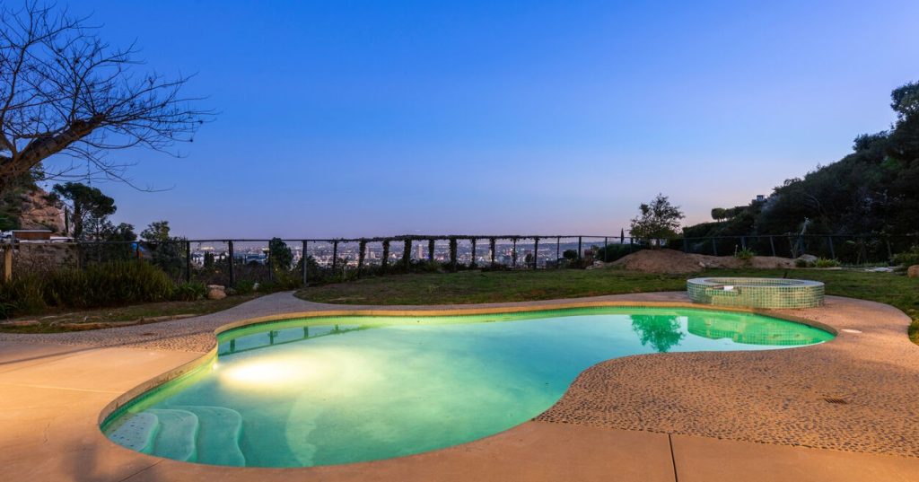 Find tranquility in your backyard oasis with a swimming pool, a flat grassy lawn, and breathtaking canyon and city views.