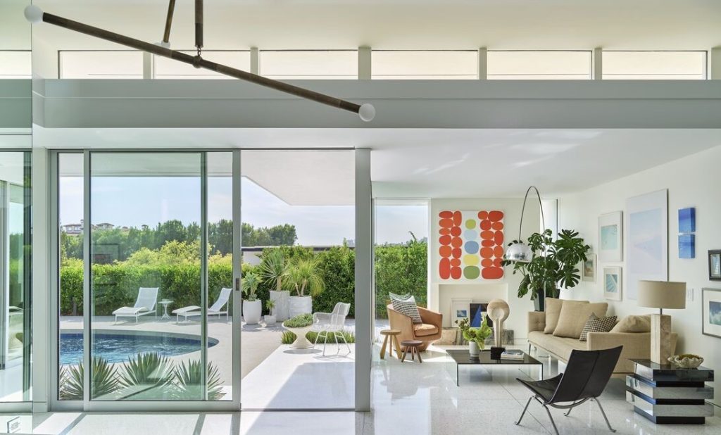 Walls of glass open to an iconic pool and manicured grounds.