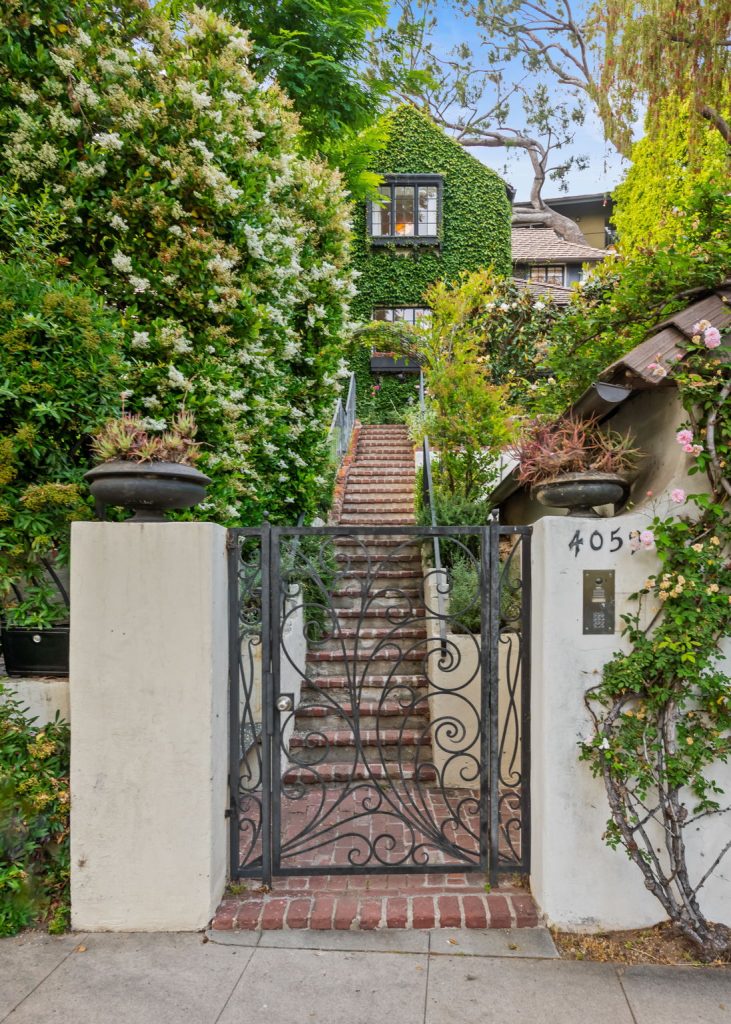 Perched above the street behind a gate, the property unfolds into a majestic garden setting meticulously manicured and cared for by its current owner.