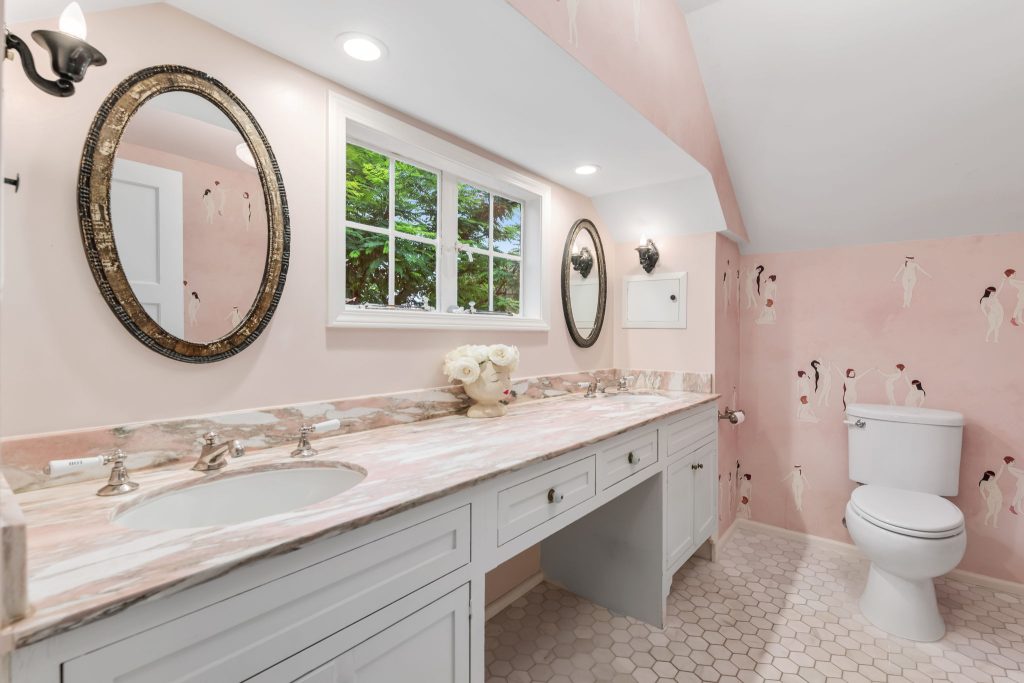 A custom designed bathroom featuring a rose quartz vanity is truly spectacular. The elegant wallpaper by Maison C was designed specifically for this primary bathroom.