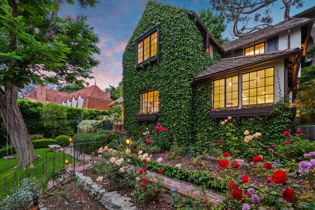 Perched above the street behind a gate, the property unfolds into a majestic garden setting meticulously manicured and cared for by its current owner.