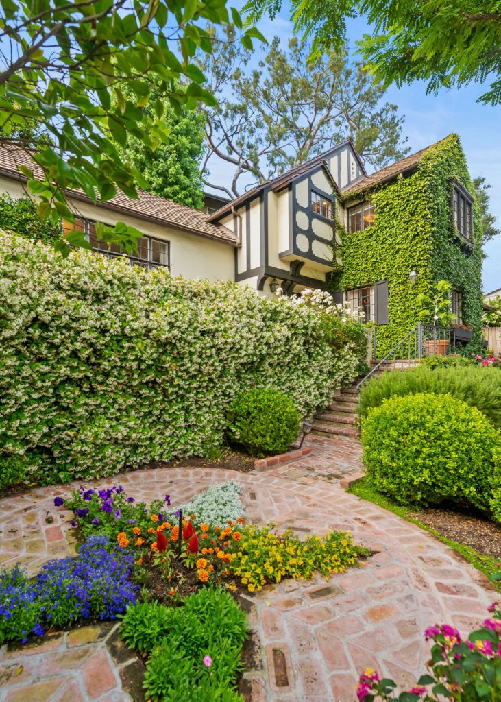 Perched above the street behind a gate, the property unfolds into a majestic garden setting meticulously manicured and cared for by its current owner.