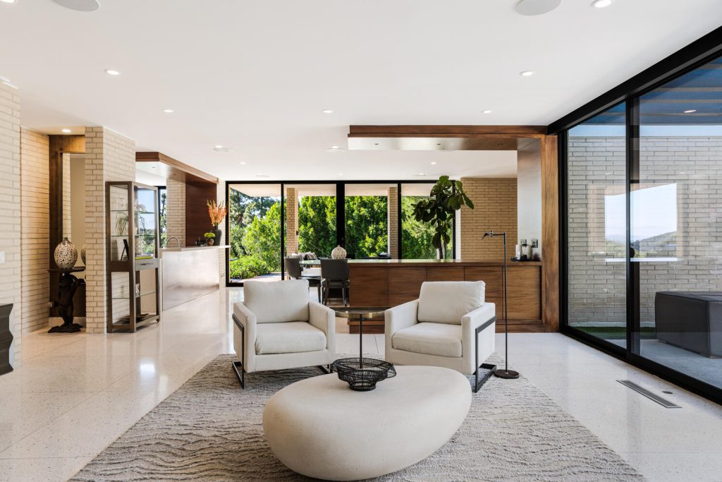 The living room boasts brick posts, a groovy wooden room divider and an expansive geometric skylight.