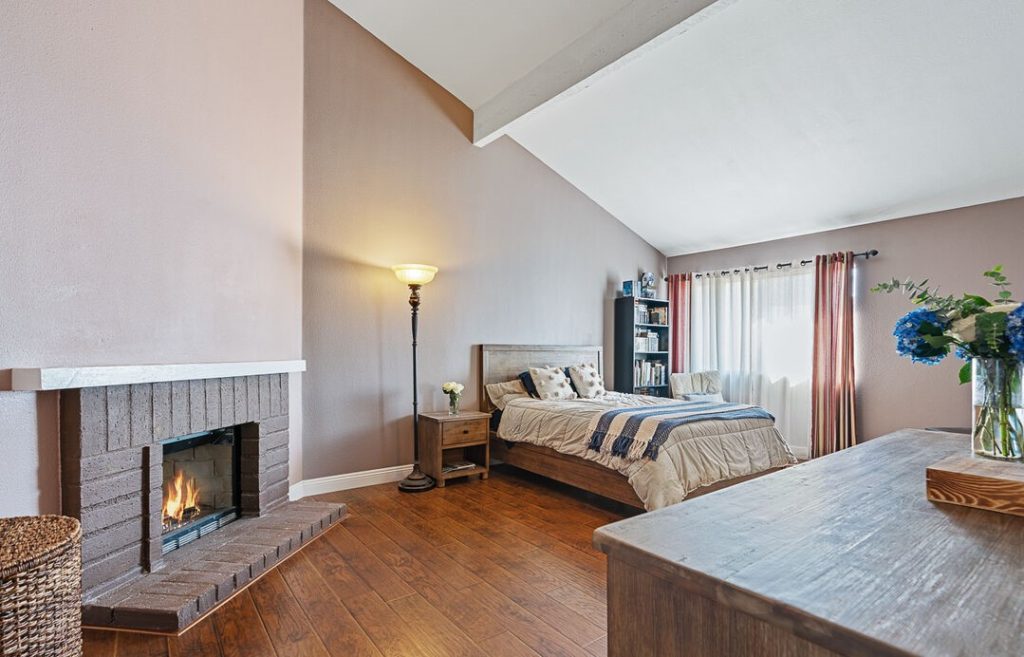 spacious primary bedroom with high ceilings, fireplace, and an en-suite bathroom.
